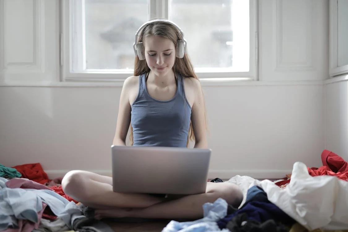 A woman listening to music along while using a laptop