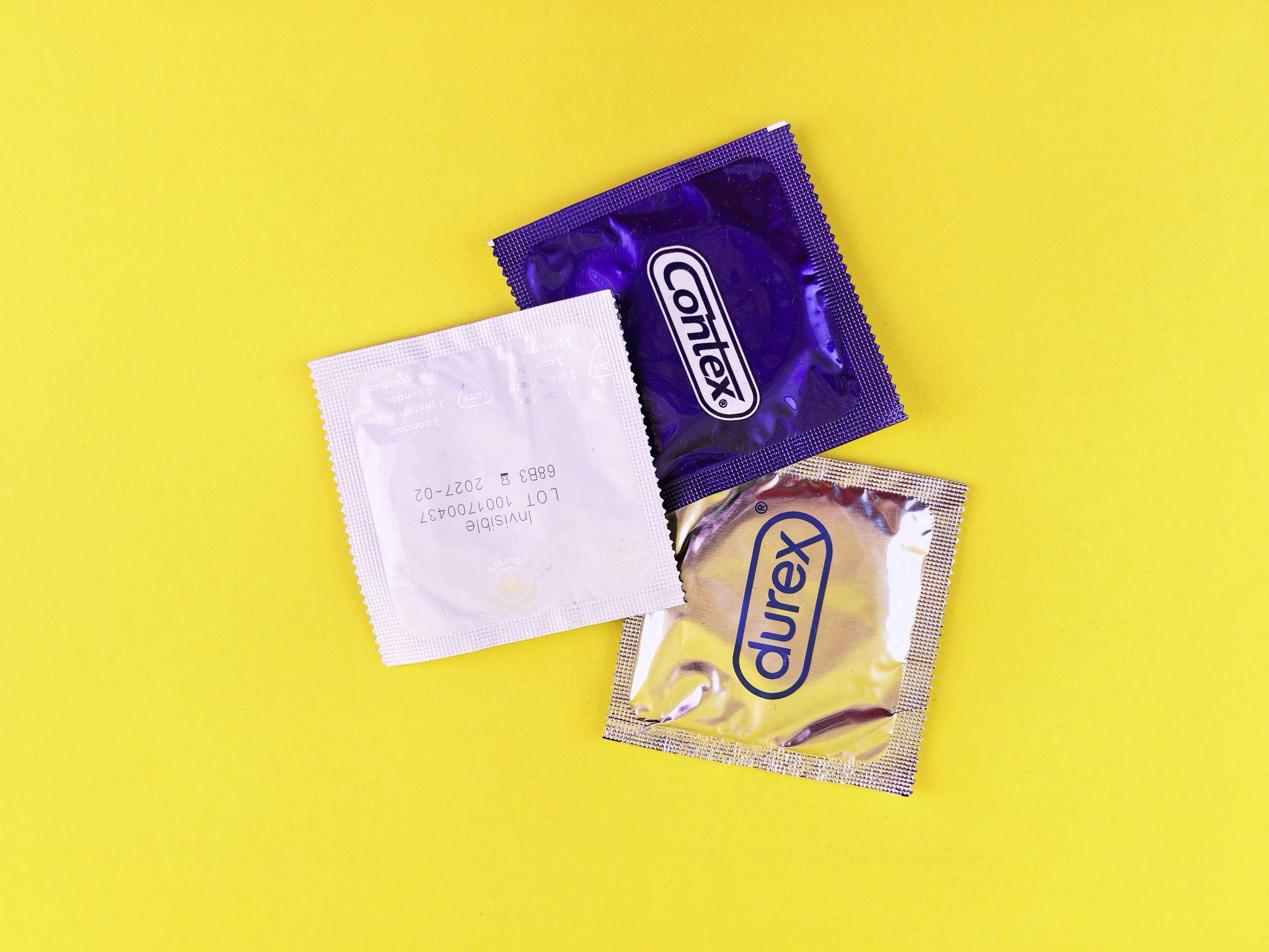 Three different brands of condoms laid out on a yellow background