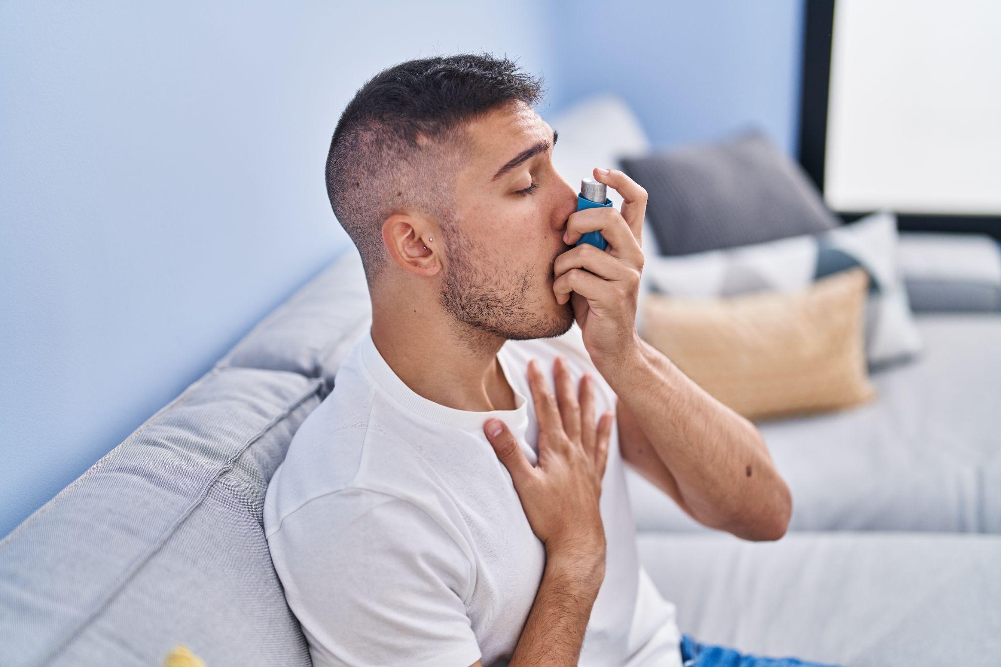 A man using an inhaler while sitting on a couch