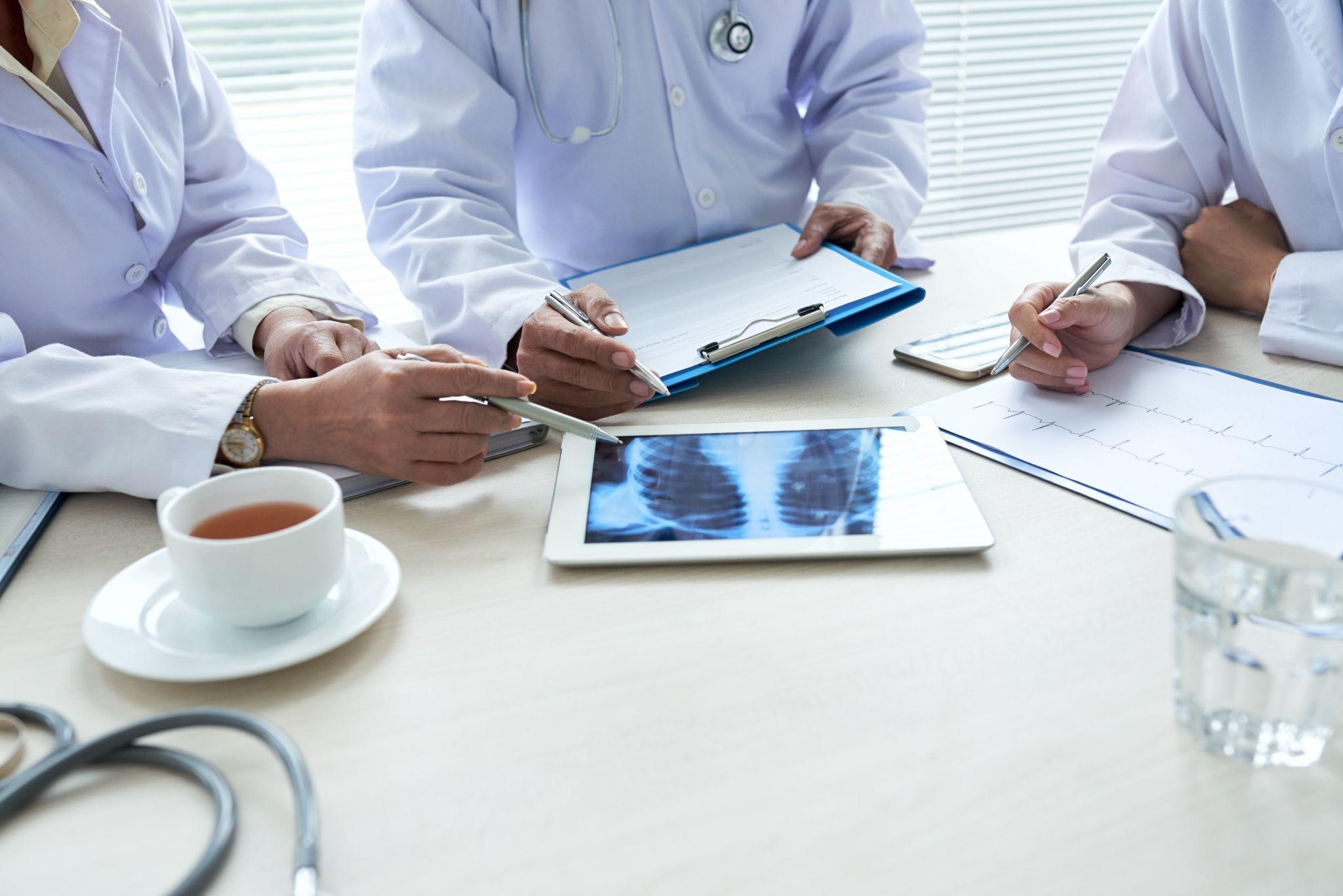 A group of doctors reviewing an X-ray on a tablet during a medical consultation.