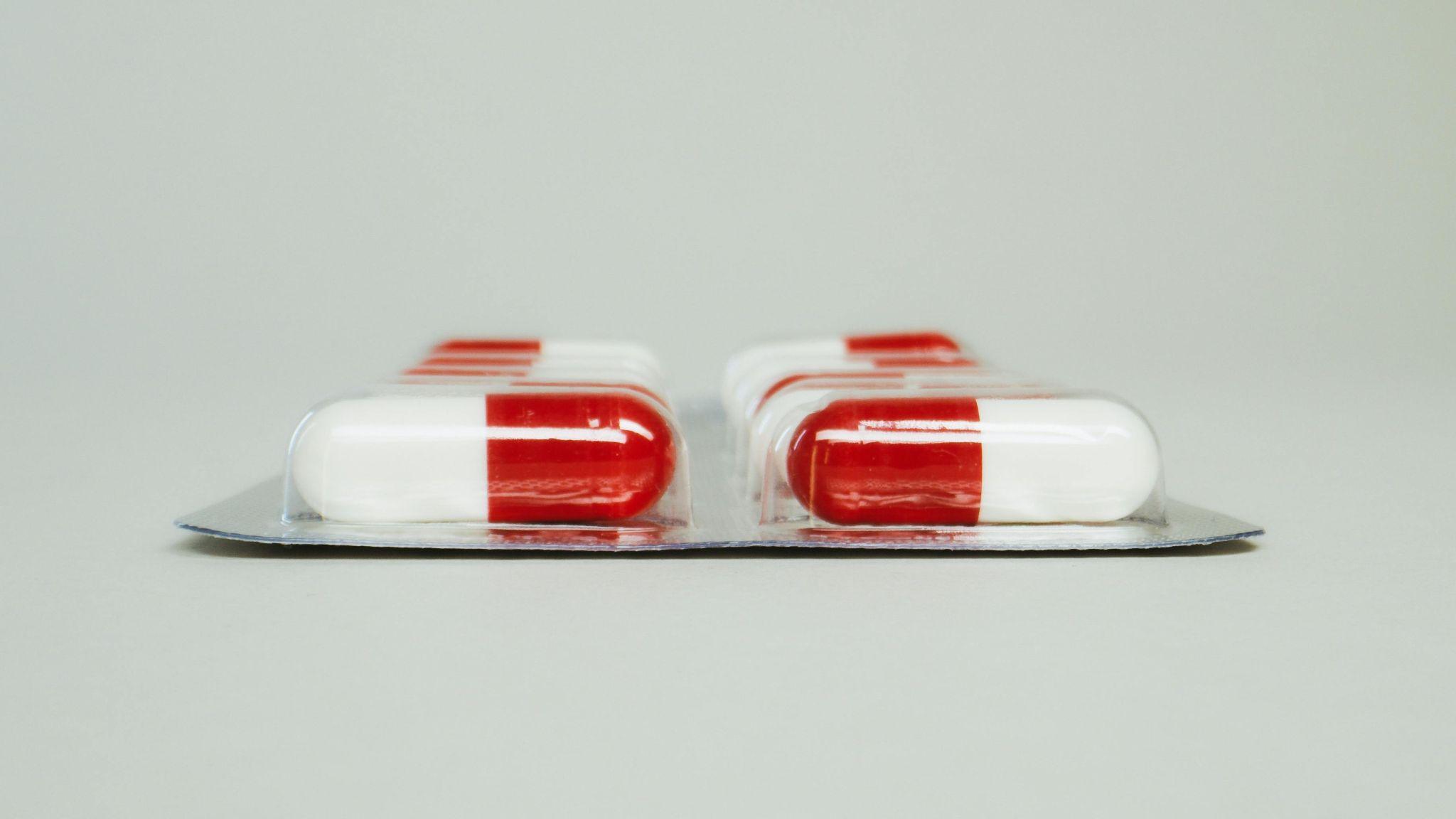 Close-up of red and white capsules arranged in a blister pack.