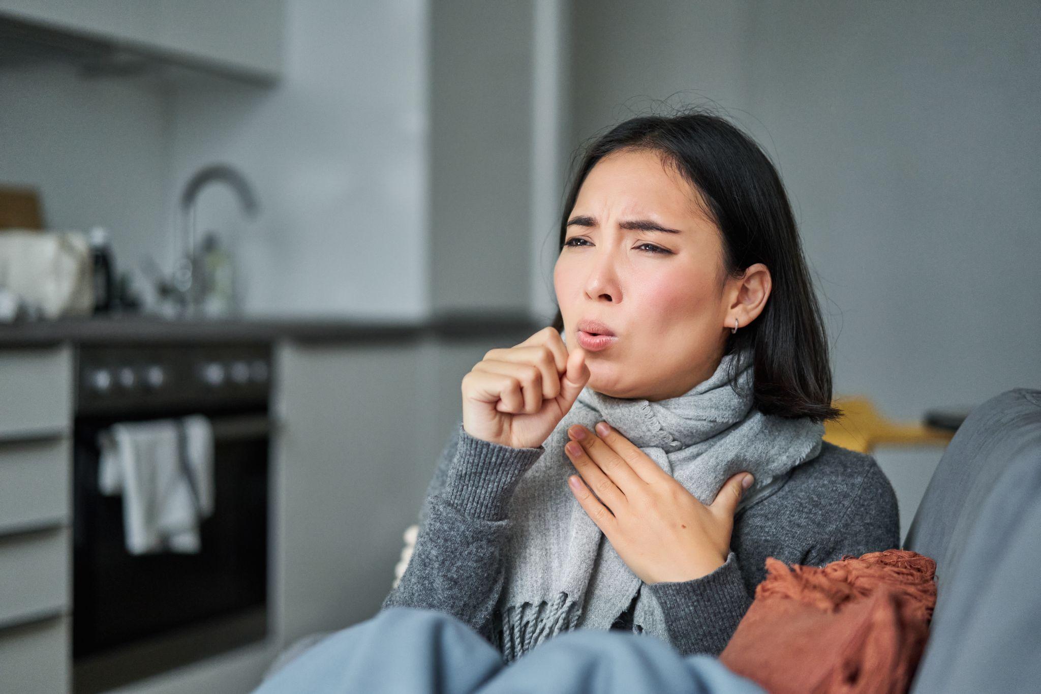 A woman coughing and holding her throat