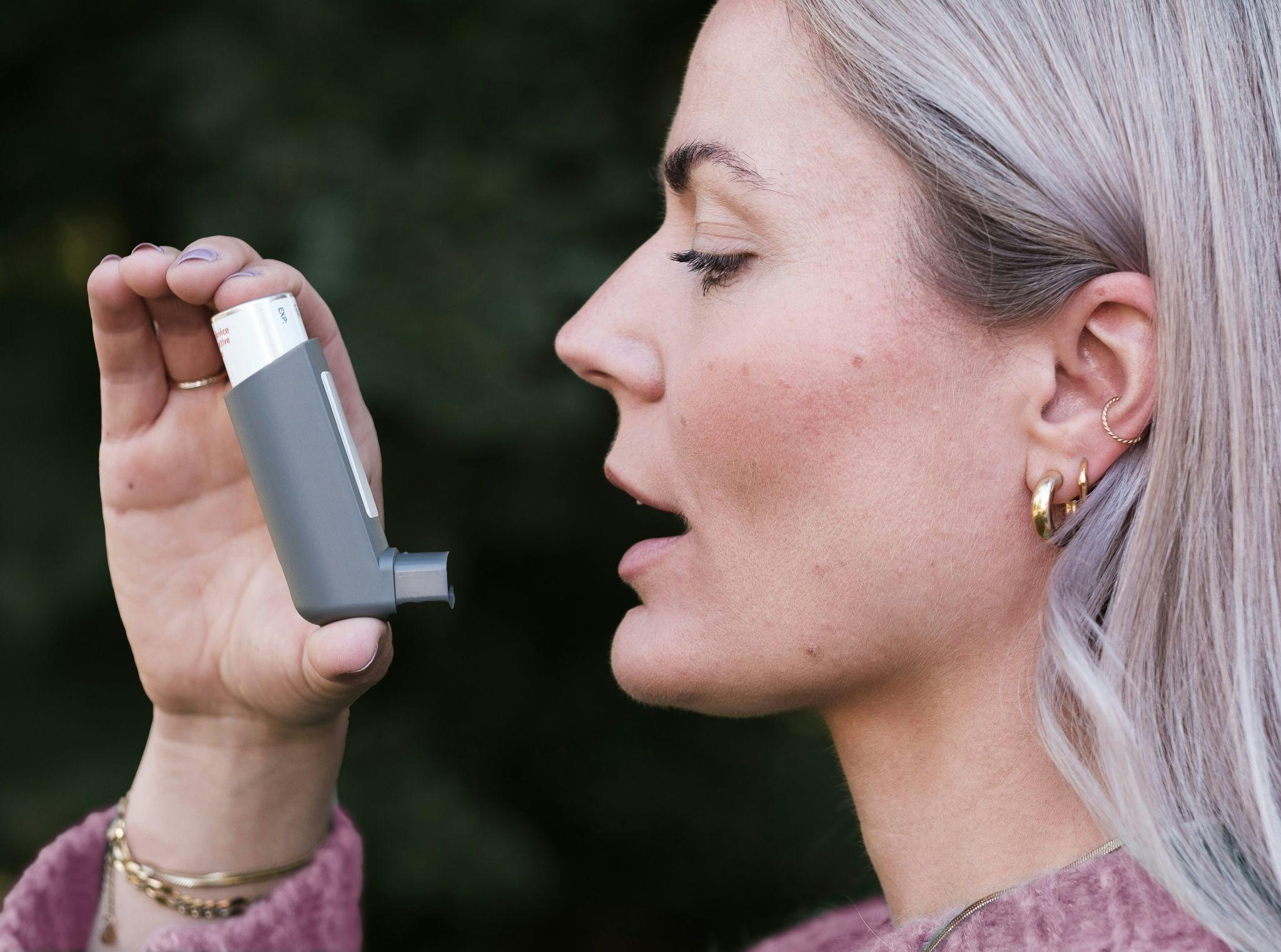 A woman using an inhaler, managing asthma.