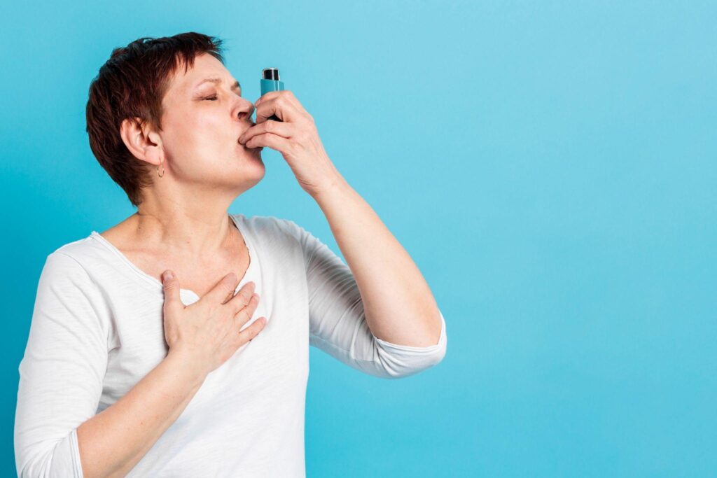 A woman using an inhaler, holding her chest in discomfort