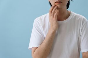 A person in a t-shirt tenderly touching their face 