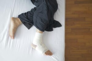 Close-up of a foot with a bandage while person rests on a bed