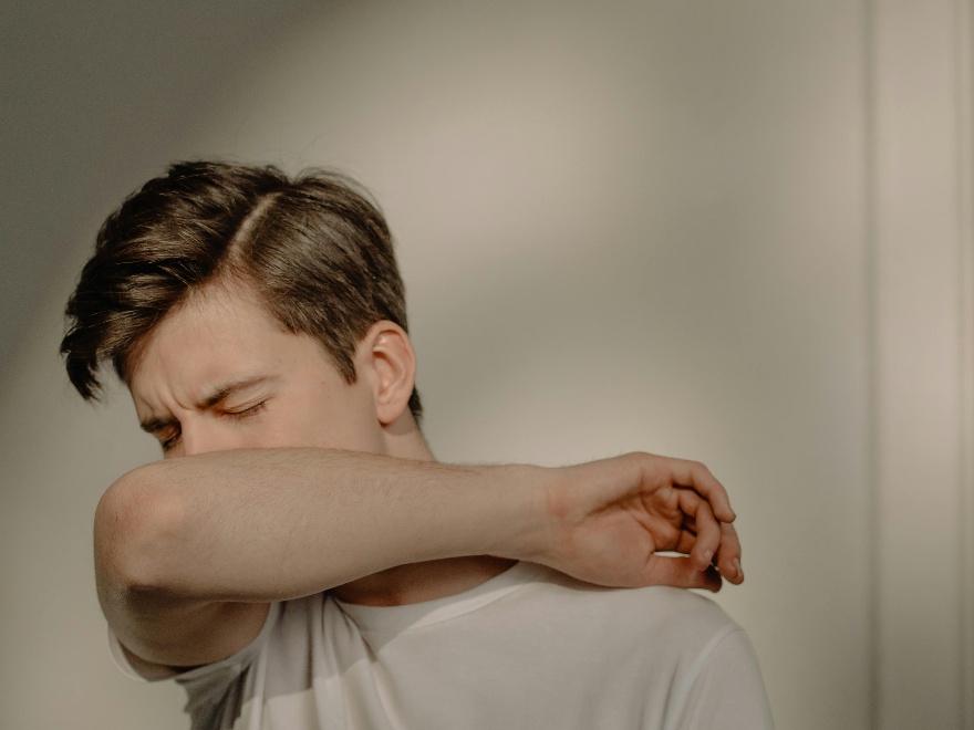 Man sneezing into his elbow