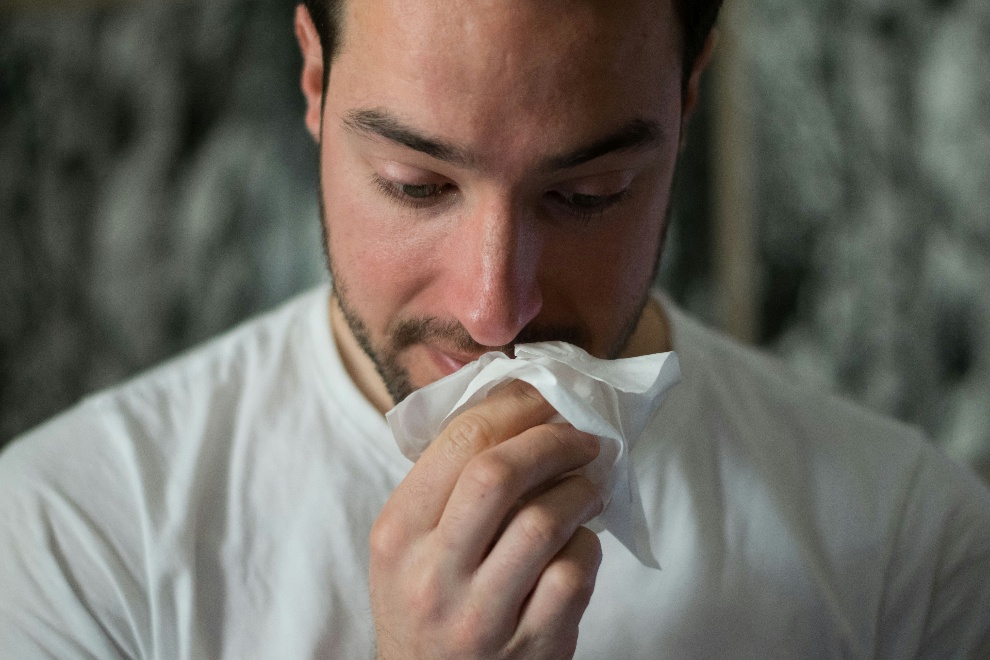 Man about to wipe his nose with a tissue