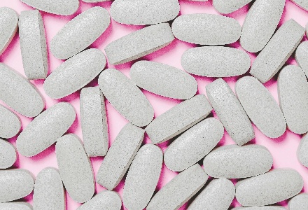 White pills against a pink background 