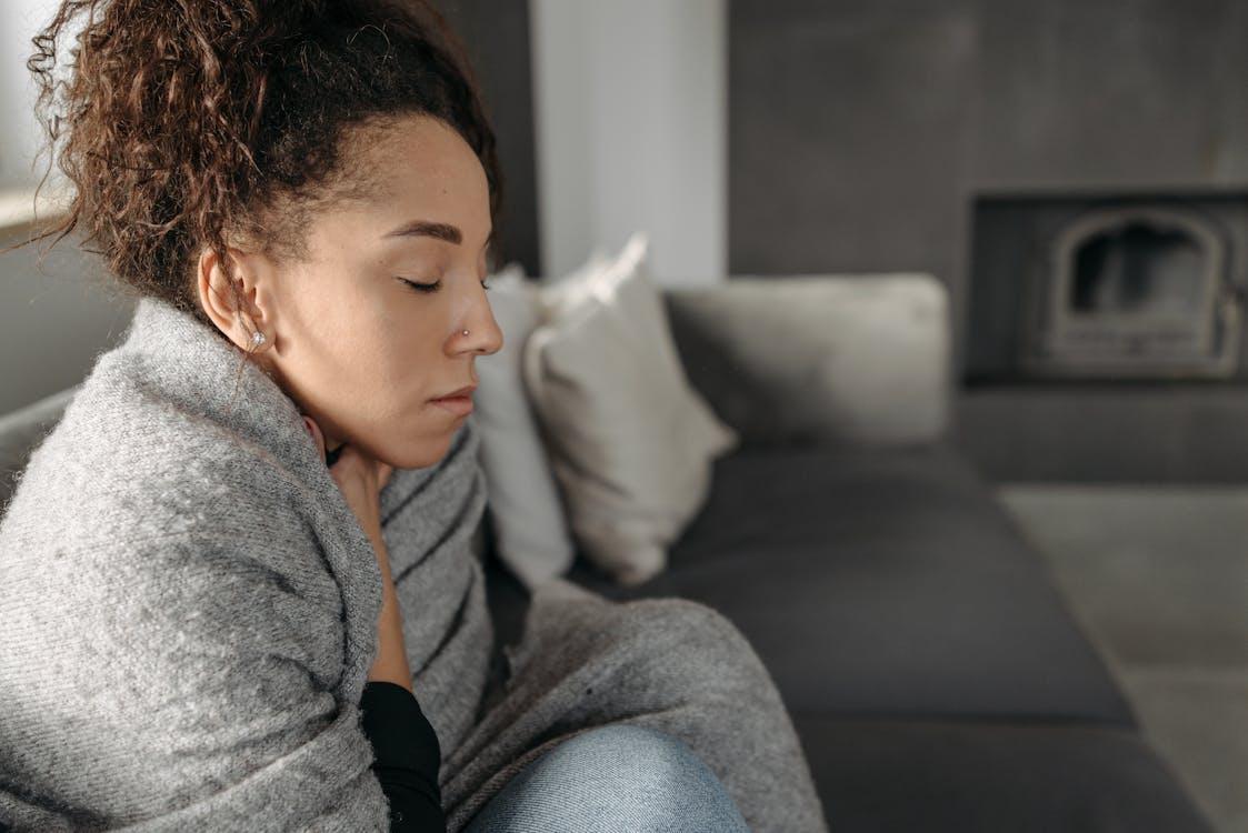 A sick woman sitting on the couch.