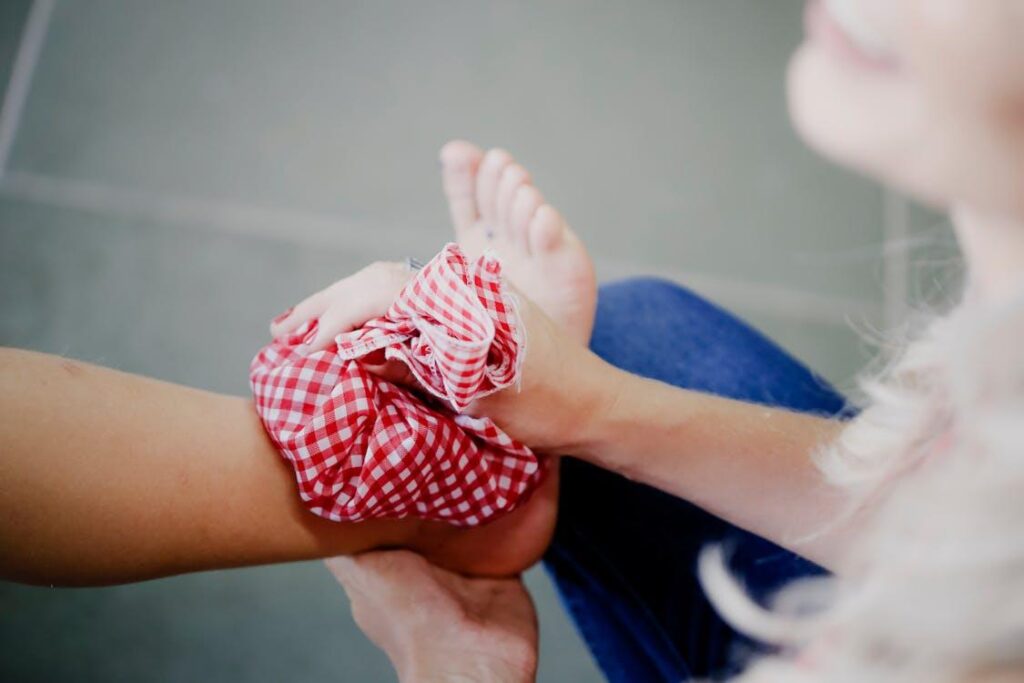 An image of a woman icing a person’s ankle after injury