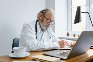 elderly doctor writing a doctor’s note
