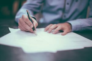 A person writing a doctor’s note on paper
