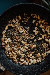 An image of a black pan with assorted nuts and seeds