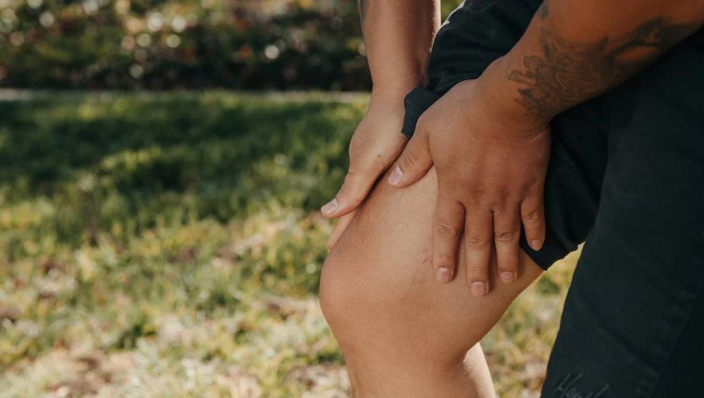 An image of a man holding his leg in pain 
