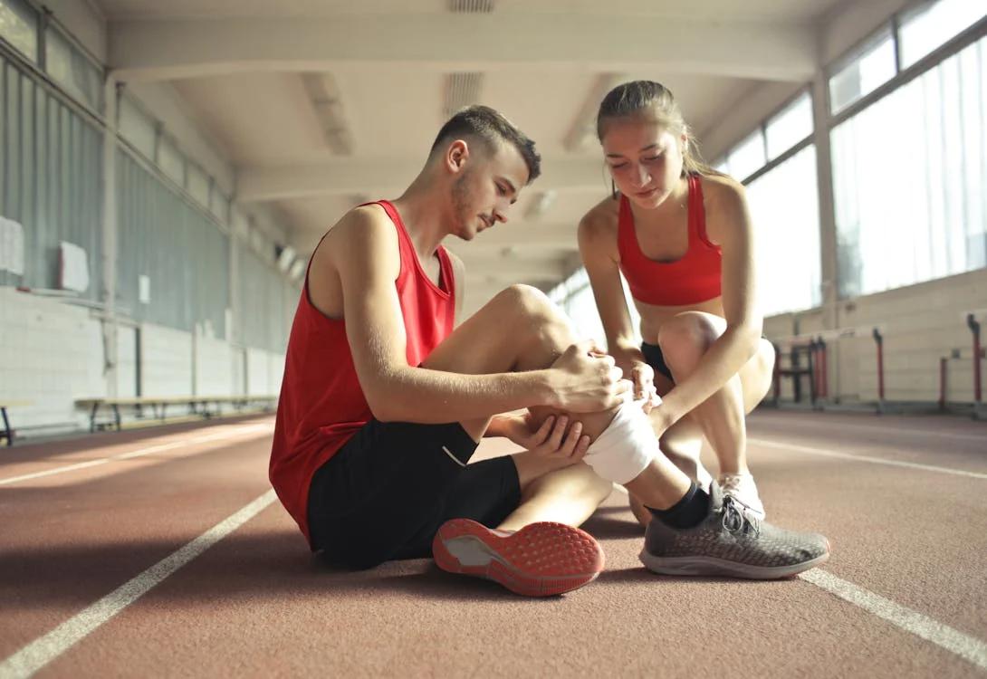 An image of a woman helping a man with his injured leg after a run 