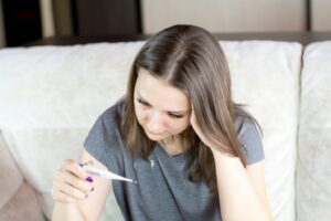 A woman looking at a thermometer