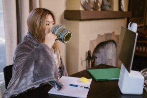 woman drinking coffee while using laptop