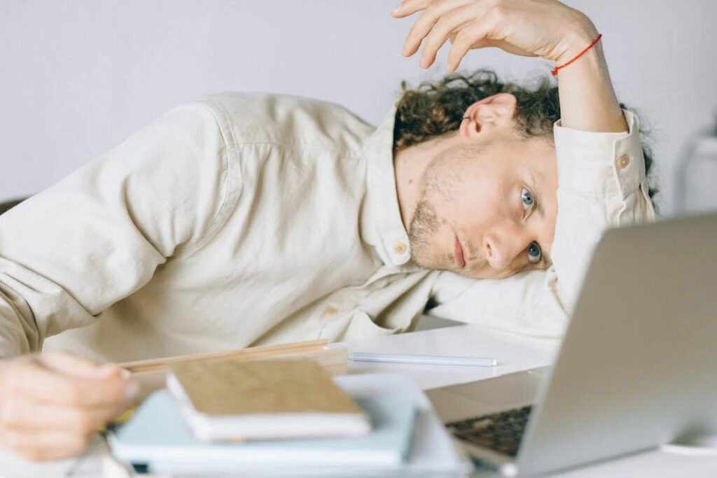 An image of an overworked employee lying in front of his laptop