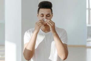 a man wiping his nose with a tissue