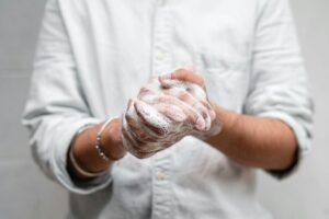 Person washing hands with soap and lather covering both hands.