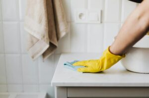 A person cleaning a surface in the bathroom.