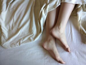 close-up of feet resting under light-colored blankets