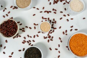 Bowls filled with beans, rice, and grains placed on a white surface.