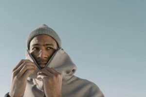 man pulling up his hoodie while standing outside in cold air
