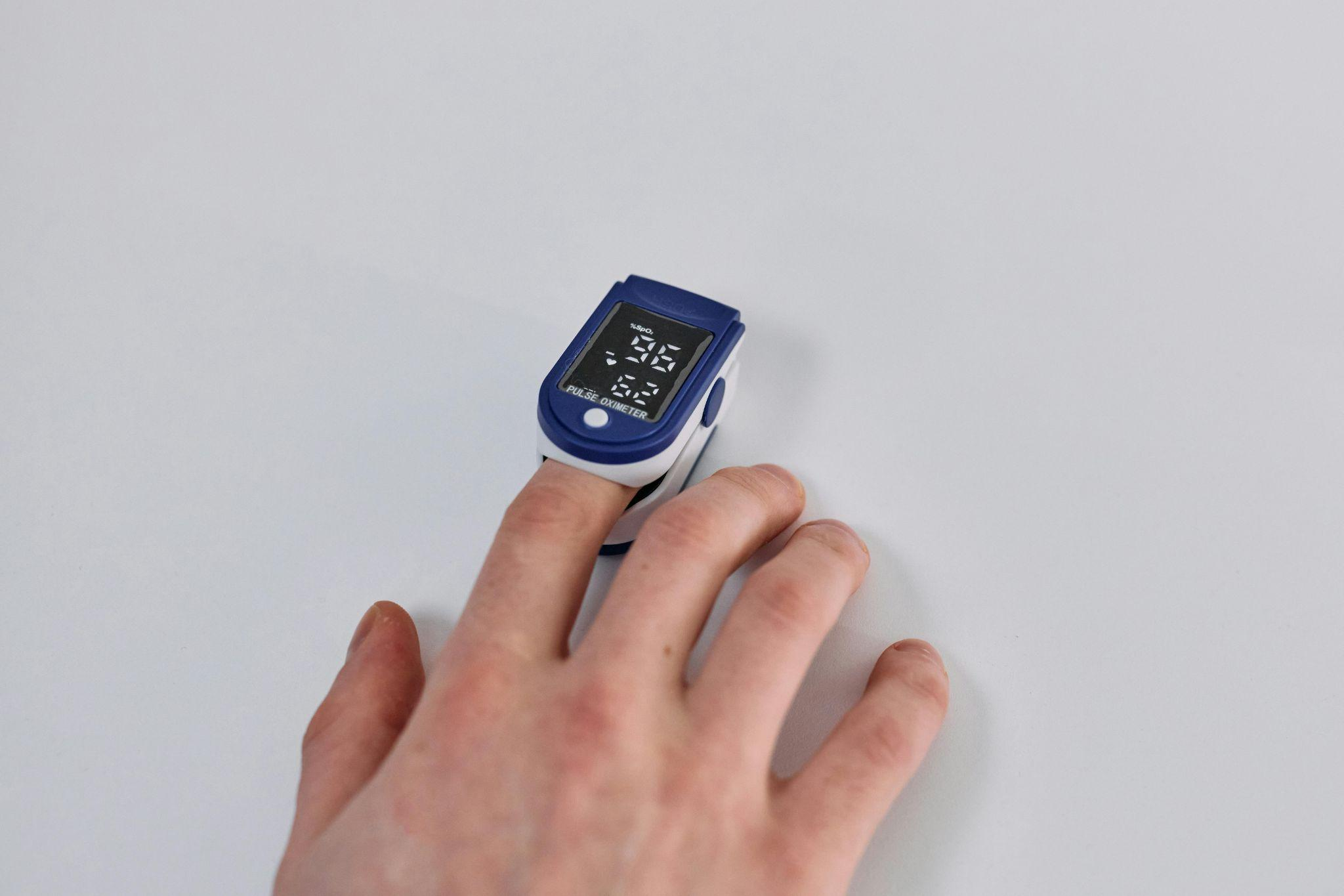 Hand wearing a fingertip pulse oximeter.