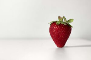 Fresh strawberry displayed on a plain white surface.