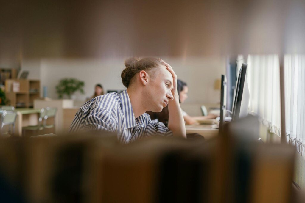 Man sitting at a desk with his head in his hand, appearing mentally exhausted.