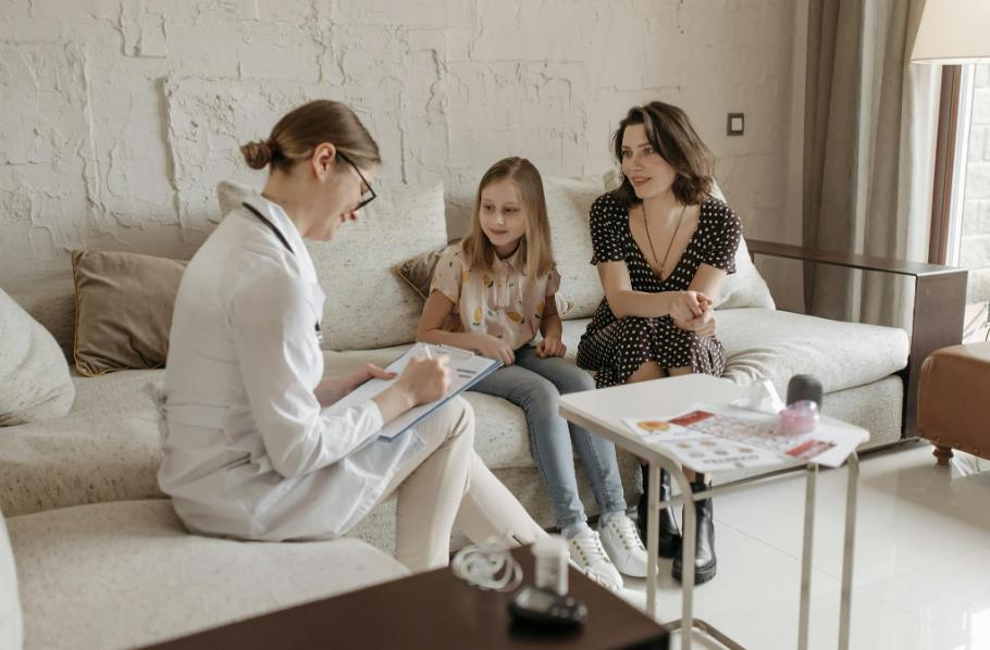 The image shows a doctor preparing a school absence note for a child.