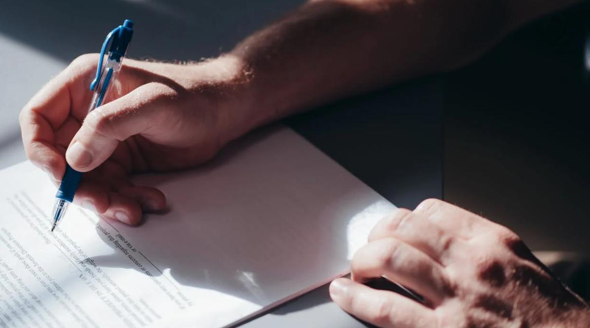 This image shows a person holding a paper and writing on it