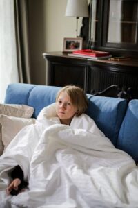 a child with blonde hair sitting on the couch.