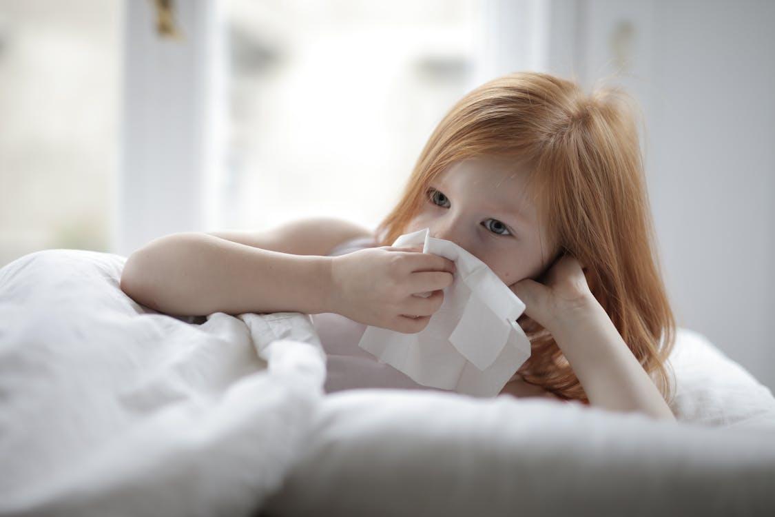 Child resting in bed with tissues during a common cold