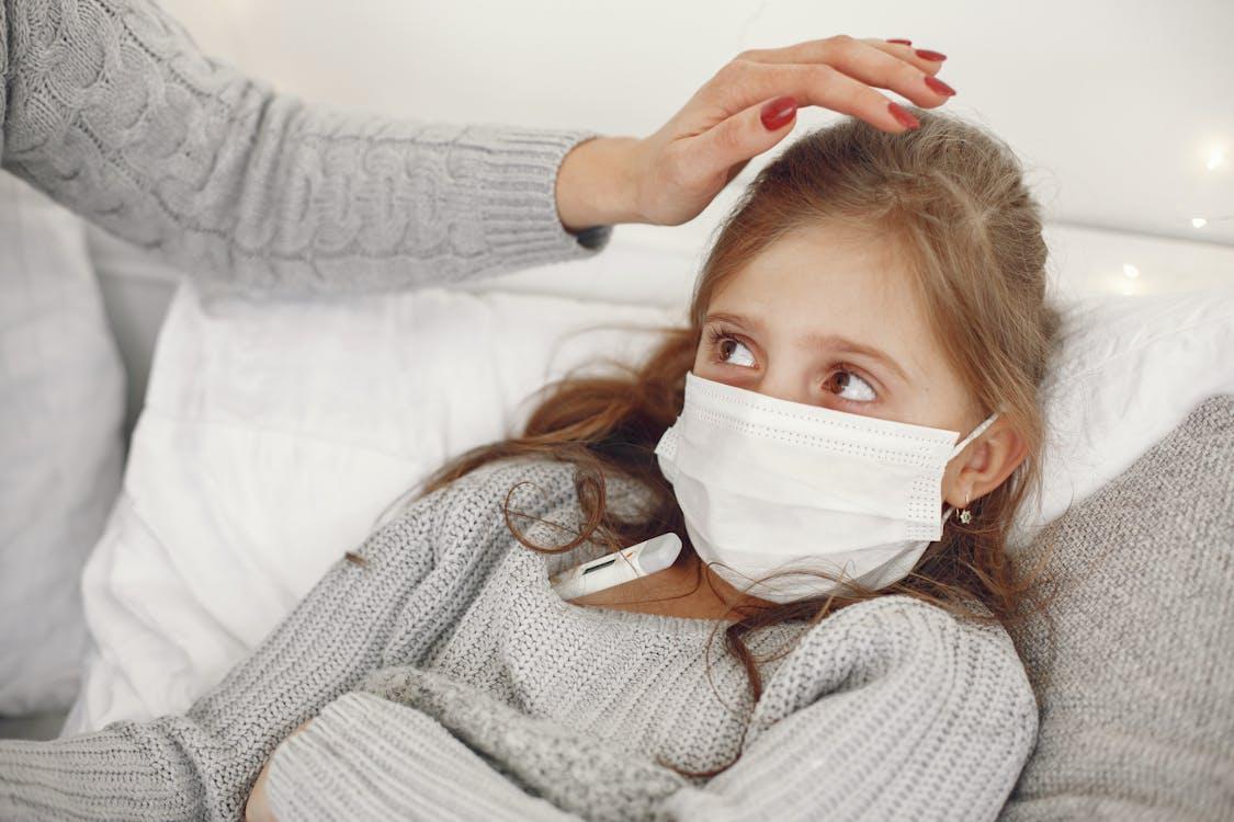 Child wearing a face mask while resting at home during illness