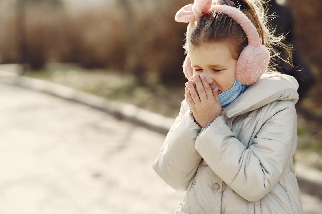 Child bundled up outdoors with cold symptoms during seasonal illness