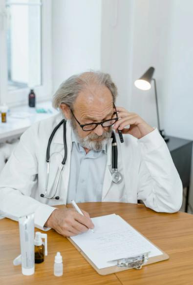 This image shows a doctor wearing eyeglasses writing on the paper.