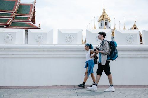 Man and woman walking beside a concrete fence outdoors