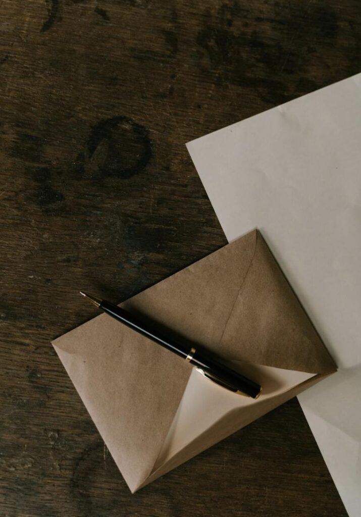 This photo shows a wooden desk with a paper document, envelope, and pen placed neatly.