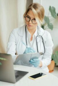 This image shows a female doctor writing notes during a consultation.