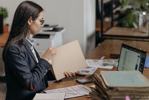 Employer reviewing employee documentation on a laptop and holding printed papers