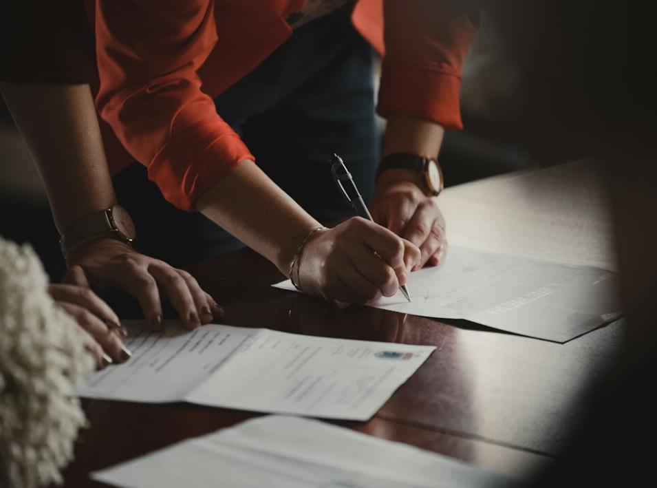 This image shows a person in orange shirt writing on white paper.