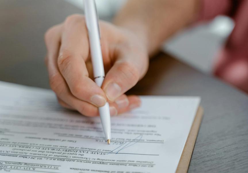 This image shows a person signing on a paper.