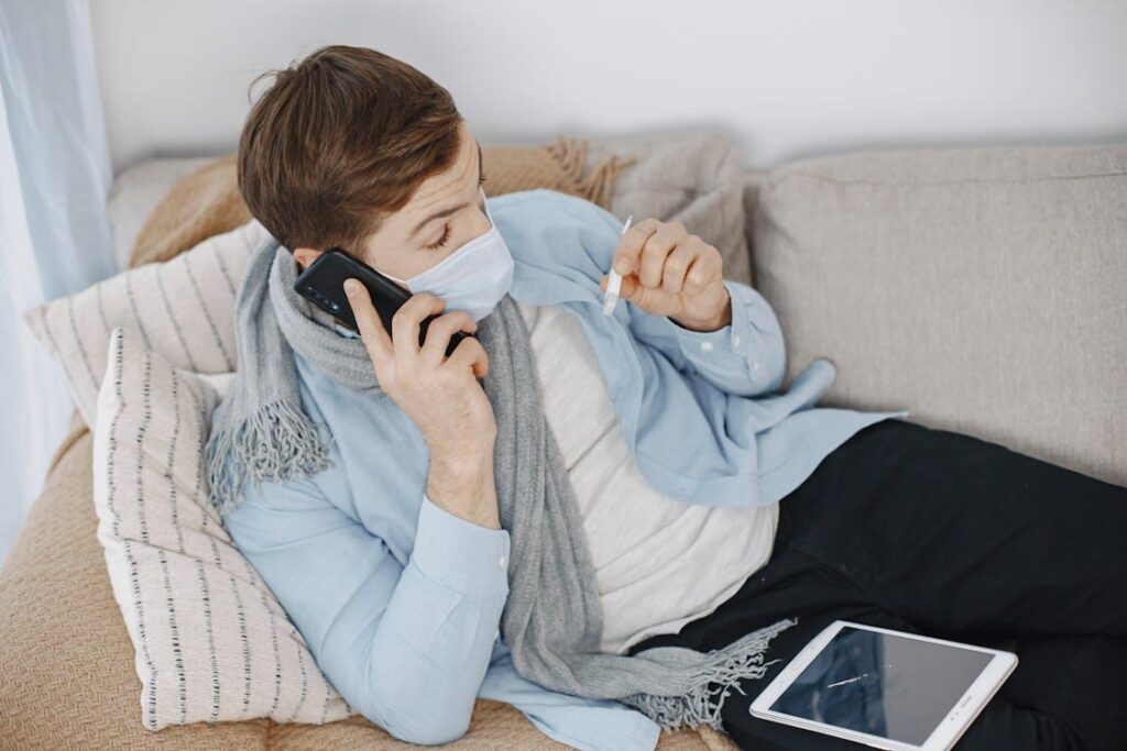 Sick employee resting at home while checking temperature and arranging online FMLA certification documentation.