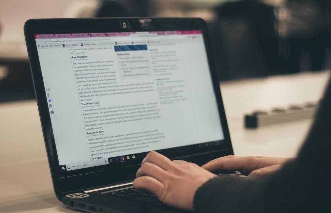 This image shows a person typing and reviewing a document on laptop.