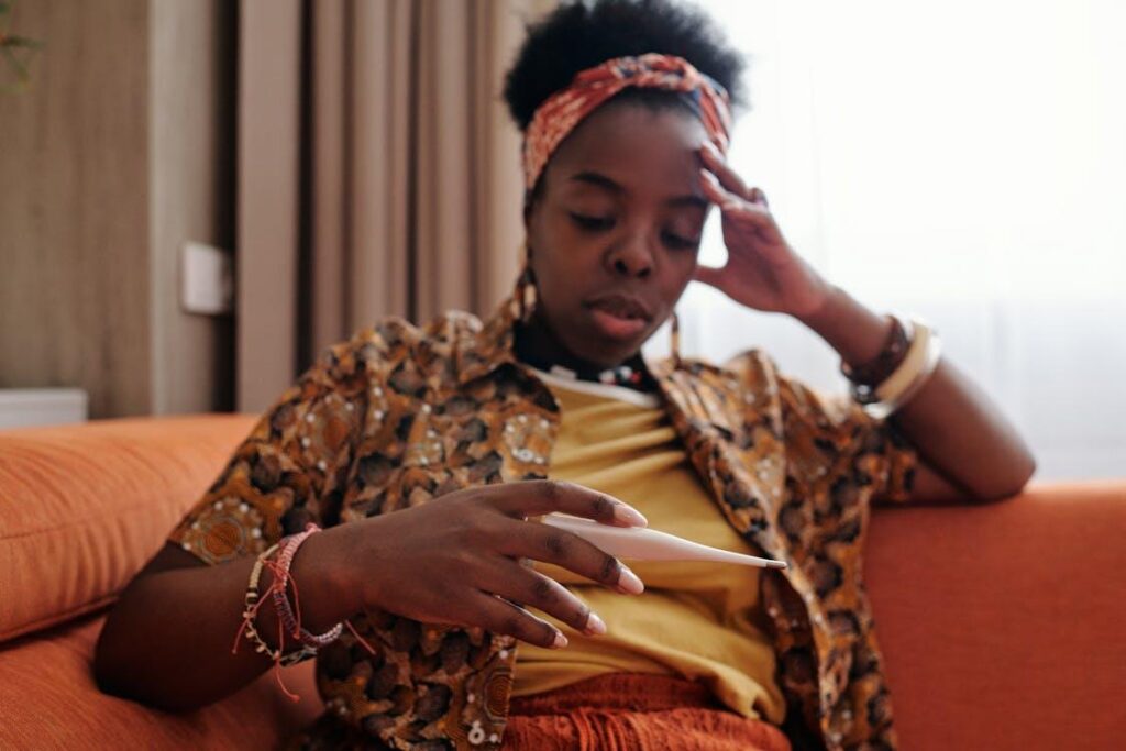 Woman sitting on a couch holding a thermometer