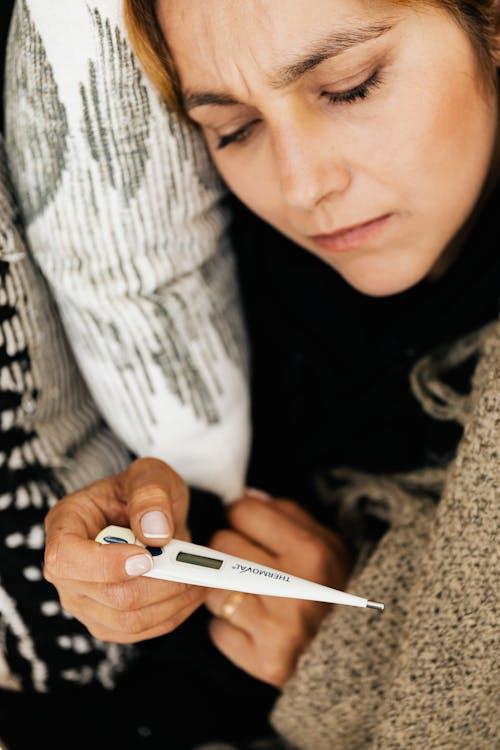 Sick woman using a digital thermometer to check temperature